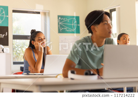 In high school, teenagers using laptops and listening attentively in classroom In high school, teenagers using laptops and listening attentively in classroom 117214222