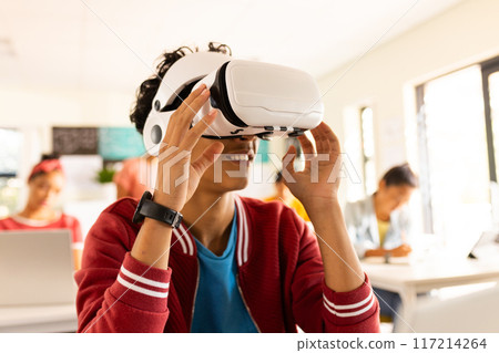 In high school, teenage boy using VR headset in classroom, exploring virtual reality 117214264