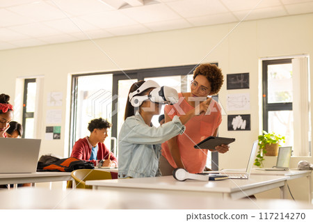 In high school, teacher guiding student using VR headset and tablet in classroom In high school, teacher guiding student using VR headset and tablet in classroom 117214270