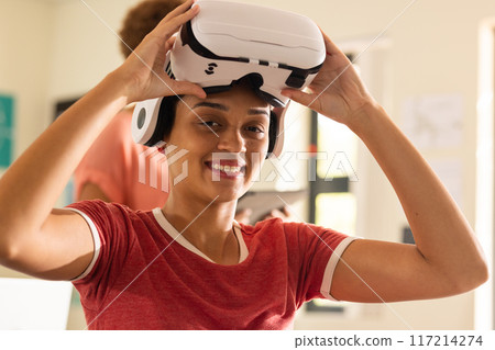 Using VR headset, smiling teenager in high school classroom, enjoying virtual experience 117214274