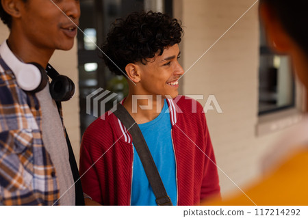 Teenage boy in high school smiling and talking with friends, wearing casual clothes Teenage boy in high school smiling and talking with friends, wearing casual clothes 117214292