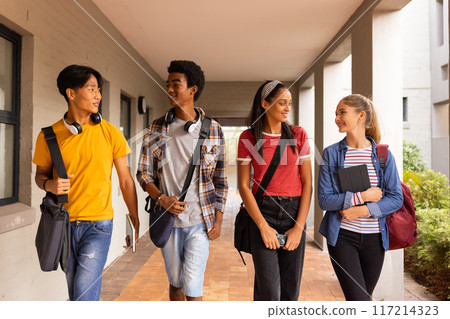Walking in high school hallway, group of teenagers talking and carrying backpacks Walking in high school hallway, group of teenagers talking and carrying backpacks 117214323