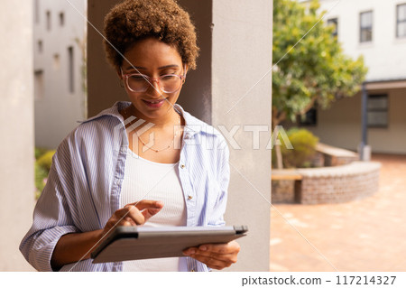 Using tablet, teenage girl studying outside high school building, focusing on screen Using tablet, teenage girl studying outside high school building, focusing on screen 117214327