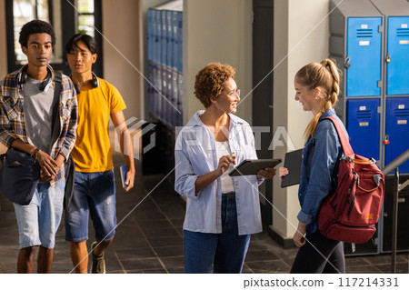 Teacher using tablet talking to student in high school hallway with lockers Teacher using tablet talking to student in high school hallway with lockers 117214331