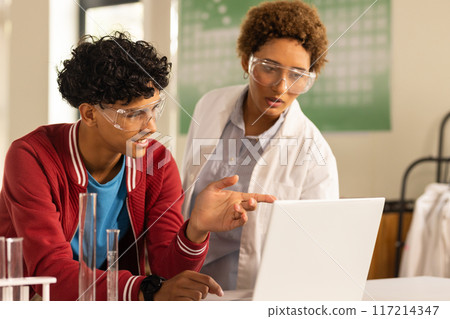 In high school, teenagers using laptop and discussing science project in laboratory In high school, teenagers using laptop and discussing science project in laboratory 117214347