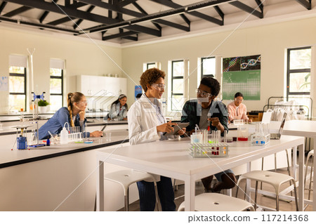 Conducting experiments and discussing results with classmates in high school laboratory Conducting experiments and discussing results with classmates in high school laboratory 117214368