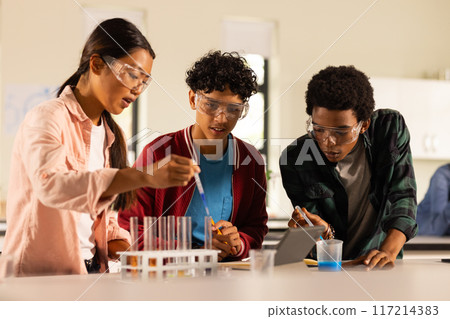 Conducting science experiment with test tubes and safety goggles, teenagers in high school 117214383