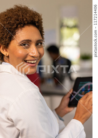 In high school, teacher holding tablet and smiling in classroom, engaging in learning In high school, teacher holding tablet and smiling in classroom, engaging in learning 117214406