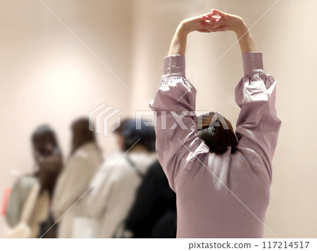 Women waiting in line and the woman at the end stretching Women waiting in line and the woman at the end stretching 117214517