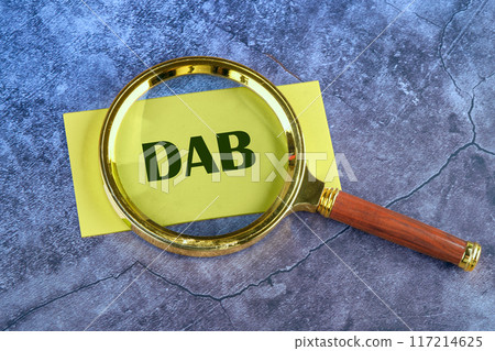 DAB Written appeared through a magnifying glass on yellow paper on an abstract background 117214625