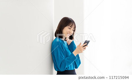 Smiling Japanese businesswoman looking at her smartphone Smiling Japanese businesswoman looking at her smartphone 117215094