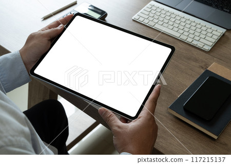 A businessman holds a mockup. iPad digital tablet with blank screen Mockup replaces your design mockup in the office. 117215137