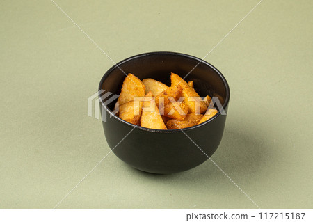 Portion of baked potato wedges in black bowl 117215187