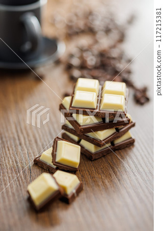 White light dark chocolate bars on wooden table. 117215381