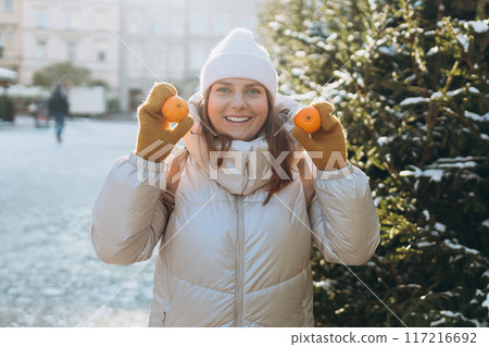 Happy and carefree smiling, laughing lovely redhead girl holding mandarins and having fun. Winter holidays banner. Concept of vacations, holidays and happiness Christmas. High quality photo 117216692