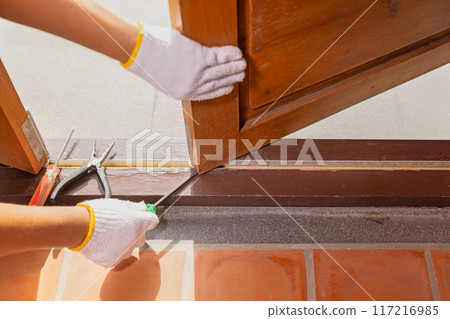 Handyman fixing roller stuck in buttom track of folding door. Handyman fixing roller stuck in buttom track of folding door. 117216985