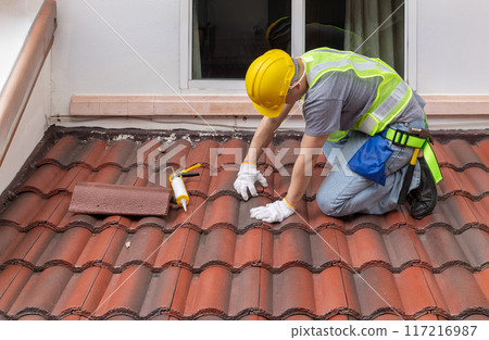 Construction worker is inspecting roof tile cracked. 117216987