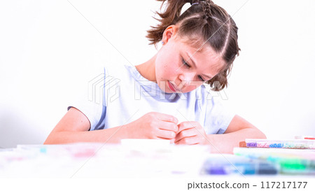 Delicate fingers of a young girl navigate through a treasure trove of bright, multicolored beads, each compartment revealing a new hue to choose from. She's immersed in the joyful task of stringing Delicate fingers of a young girl navigate through a treasure trove of bright, multicolored beads, each compartment revealing a new hue to choose from. She's immersed in the joyful task of stringing 117217177