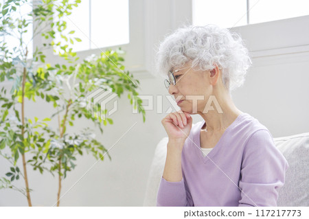Worried senior woman in living room Worried senior woman in living room 117217773