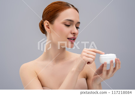 Pretty young woman trying a new face cream and looking relaxed and enjoyed 117218084