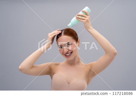 Young woman using a new shampoo and looking happy Young woman using a new shampoo and looking happy 117218086