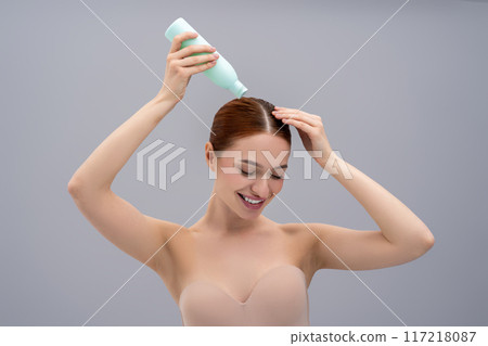Young woman using a new shampoo and looking happy 117218087