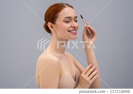 Portrait of a smiling young woman with an eyebrow brush in hands 117218098