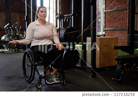 Full length portrait of active woman with disability using exercise machines in gym copy space Full length portrait of active woman with disability using exercise machines in gym copy space 117218258