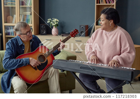 Front view portrait of senior people duo playing music and singing together enjoying creative hobby in retirement home 117218303
