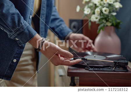 Closeup of unrecognizable senior man setting up record player at home and enjoying music old fashioned way copy space Closeup of unrecognizable senior man setting up record player at home and enjoying music old fashioned way copy space 117218312
