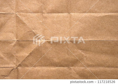 Wrinkled brown old paper with frayed folds and a contrasting texture. Dusty wrapping kraft sheet. Abstract background. For design and titles 117218526