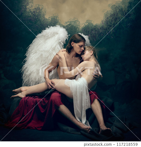 Winged male angel embraces tender woman against vintage background. Sense of tenderness and protection, blending divine with human. Winged male angel embraces tender woman against vintage background. Sense of tenderness and protection, blending divine with human. 117218559