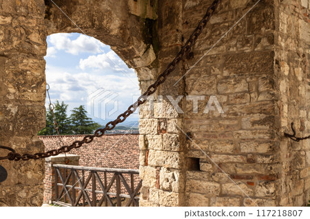 Close-up of drawbridge chain at entrance of historic Brescia castle, view through stone arch Close-up of drawbridge chain at entrance of historic Brescia castle, view through stone arch 117218807
