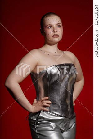 Vertical fashion portrait of young woman wearing silver outfit posing with confidence or red background Vertical fashion portrait of young woman wearing silver outfit posing with confidence or red background 117219254