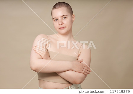 Minimal waist up portrait of smiling young girl with buzzcut and no makeup posing with confidence on neutral background in studio copy space Minimal waist up portrait of smiling young girl with buzzcut and no makeup posing with confidence on neutral background in studio copy space 117219279