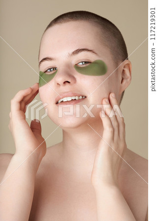 Minimal closeup portrait of smiling young woman using moisturizing patches and enjoying skincare looking at camera Minimal closeup portrait of smiling young woman using moisturizing patches and enjoying skincare looking at camera 117219301