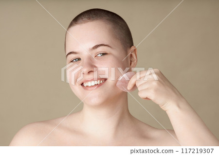 Close up portrait of smiling young woman using face massager enjoying skincare no makeup copy space 117219307
