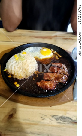 Beef blackpepper steak with sunny side up egg on a hot stone plate 117219762