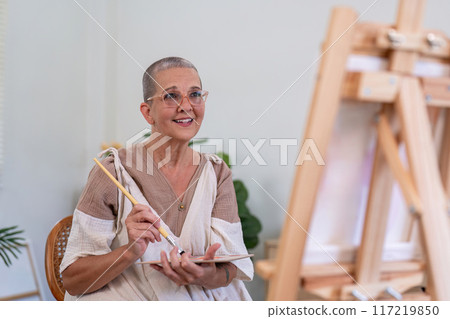 Elderly Woman Painting on Canvas at Home, Engaged in Creative Art Activity, Smiling and Happy, Senior Lifestyle and Hobby 117219850