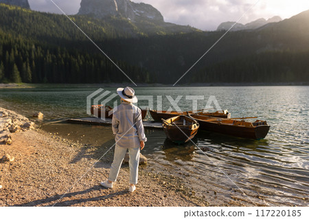 A woman in a hat looks at the boats near the Black Lake in Durmitor 117220185