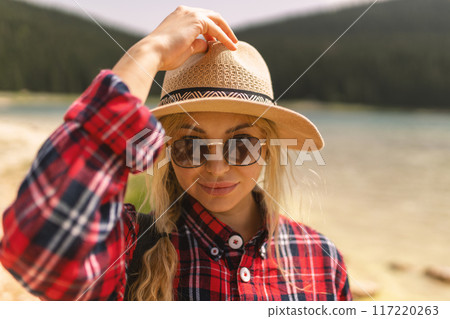 Woman traveler wearing hat and looking at amazing mountains and lake, wanderlust travel concept. black lake Montenegro. Woman traveler wearing hat and looking at amazing mountains and lake, wanderlust travel concept. black lake Montenegro. 117220263