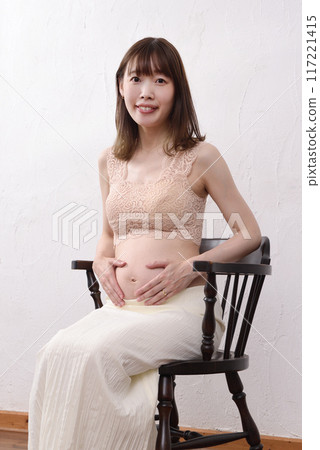 A young Japanese pregnant woman holds her hand on her big belly 117221415