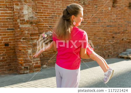 Child girl with cochlear implant with her mother spend time outdoor. Hear impairment and deaf community concept. Deaf and health concept. Disability and inclusion. Copy space 117221424