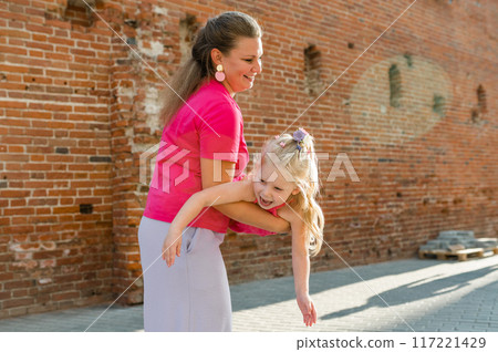 Child girl with cochlear implant with her mother spend time outdoor. Hear impairment and deaf community concept. Deaf and health concept. Disability and inclusion. Copy space 117221429