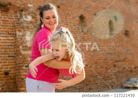 Blonde little girl with cochlear implant playing with her mother outdoor. Hear impairment deaf and health concept. Disability and inclusion. Copy space Blonde little girl with cochlear implant playing with her mother outdoor. Hear impairment deaf and health concept. Disability and inclusion. Copy space 117221430