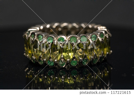 silver ring with emeralds and peridots on the background silver ring with emeralds and peridots on the background 117221615