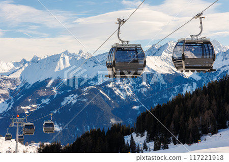 New modern spacious big cabin ski lift gondola against snowcapped forest tree and mountain peaks covered in snow landscape in luxury winter alpine resort. Winter leisure sports, recreation and travel 117221918