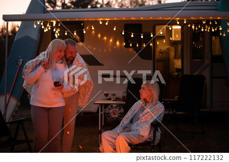 The family is relaxing together by the campfire near their mobile home. Evening family vacation The family is relaxing together by the campfire near their mobile home. Evening family vacation 117222132