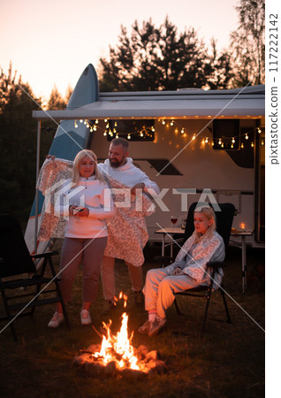 The family is relaxing together by the campfire near their mobile home. Evening family vacation The family is relaxing together by the campfire near their mobile home. Evening family vacation 117222142
