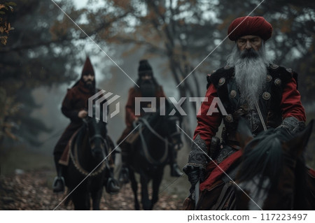 Three Cossack warriors in vibrant red attire ride their horses through a foggy forest, embodying a sense of history and adventure. 117223497